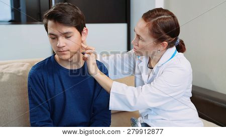 Woman Doctor Puts A Hearing Aid On A Young Guy.