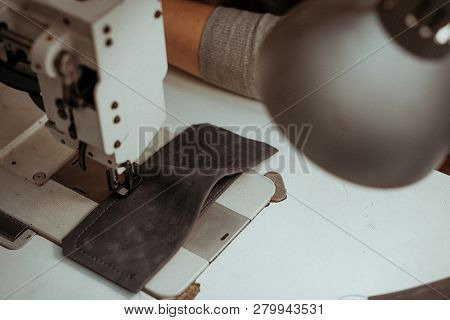 Close-up Of A Piece Of Leather Lying On A Sewing Machine On The Table In The Workshop. Handmade Mast