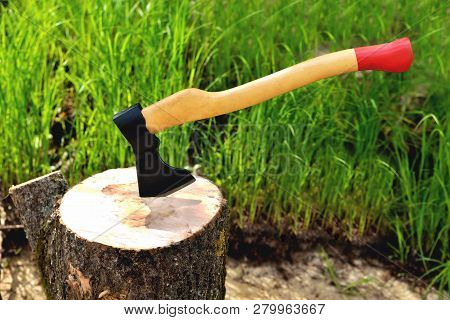 A Beautiful-shaped Ax Sticks Out In A Tree, With A Yellow Handle Close-up, On A Natural Background