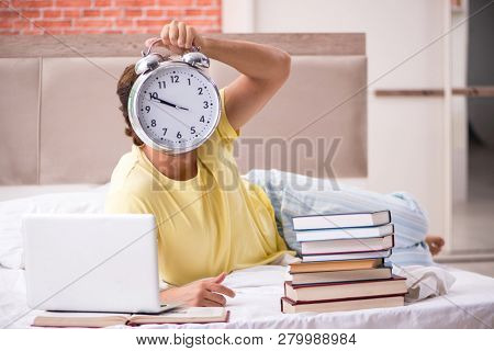 Young student studying in bed for exams