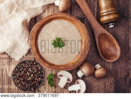 Wooden Plate Of Creamy Chestnut Champignon Mushroom Soup With Wooden Spoon, Pepper And Kitchen Cloth