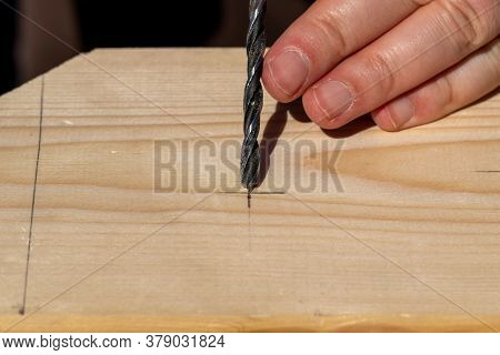 A Closeup Portrait Of Someone Aiming And Placing The Tip Of A Wood Drill Bit At The Drawn Pencil Mar