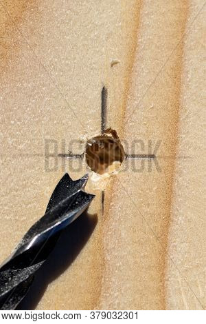 A Closeup Portrait Of A Wooden Plank With A Hole Drilled Into It On The Intersection Of The Lines Of
