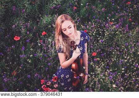 A Young Blonde European Thin Girl Stands In The Midst Of Very Tall Purple And Poppy Plant