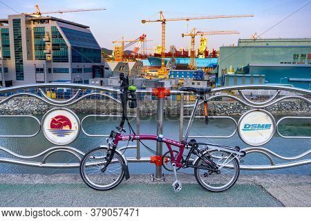 Geoje, South Korea - June 15, 2017: Brompton Folding Bike Parks On The Street Across Dsme Shipbuilde
