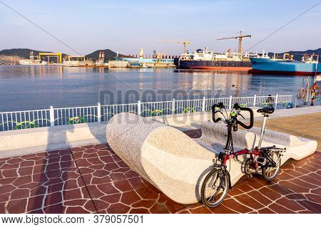 Geoje, South Korea - June 15, 2017: Brompton Folding Bike Parks On The Street Across Dsme Shipbuilde