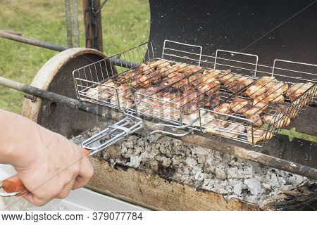 A Man's Hand Holds A Grate With Juicy Pieces Of Fresh Pork Meat Over Burning Coals. Charcoal Cooking
