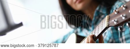 Young Woman Picks Up Guitar Chords At Home Couch. Quality Distance Education During Quarantine. Tale