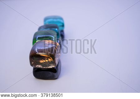 Multicolored Glass Stones Lie Vertically One After The Other On A Light Background