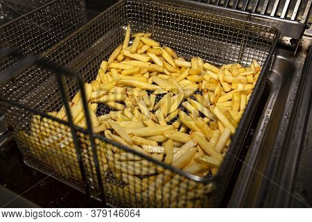 French Fries In A Deep Fryer Closeup. Fast Food Kitchen. We Drain The Oil.