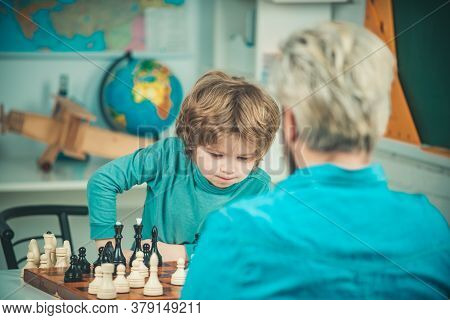 Child Early Development. Little Boy Playing Chess With Senior Man. Like Chess Game. Family Relations