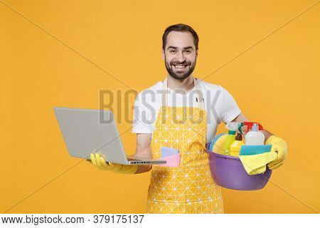 Smiling Young Man Househusband In Apron Rubber Gloves Hold Basin With Detergent Bottles Washing Clea