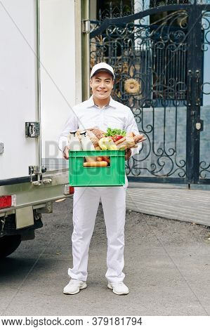Portrait Of Handsome Young Vietnamese Courier Holding Plastic Crate With Milk Bottles, Fresh Bread A