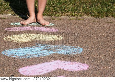 The Feet Of A Small Child Stand On A Painted Multicolored Heart. The Concept Of The Importance Of Lo