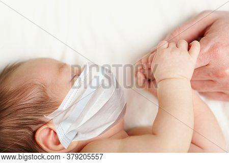 Baby In Protective Madical Face Mask Holding Fathers Hand, White Background