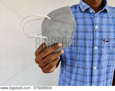 Young Man Holding One Grey Color Kn-95 Face Mask In His Hand. Blue Shirt Guy. Corona Virus Pandemic.
