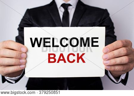 Welcome Back Inscription On A White Sheet Of Paper In The Hands Of A Businessman On A White Backgrou
