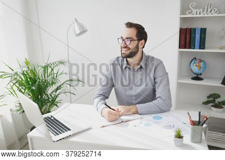 Smiling Young Bearded Business Man In Gray Shirt Glasses Sit At Desk Work On Laptop Pc Computer In L