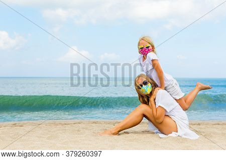 Mother, Child In Stylish Masks Have Fun On Sea Sand Beach. New Rules To Wear Face Covering At Public