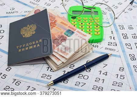 A Bundle Of Five-thousandth Bills Sticks Out Of The Work Book, Next To It Lies A Calculator And Glas