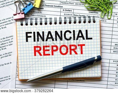 Notepad With Text Financial Report On White Background With Paper Clips And Pen