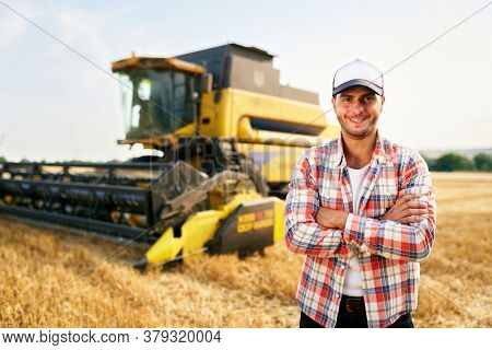 Portrait Of Proud Harvester Machine Driver With Hands Crossed On Chest. Farmer Standing At His Combi