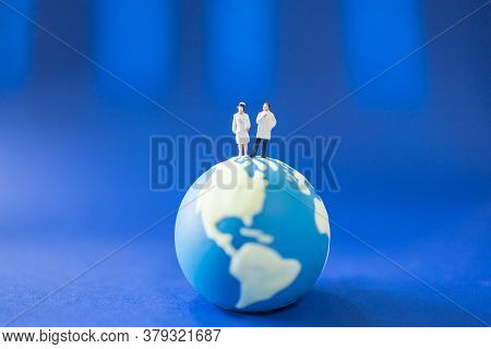 Global Healthcare Concept. Docter And Nurse Miniature Figure People With Facemask Standing On Mini W