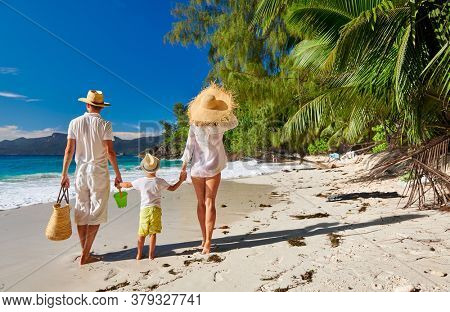 Family on beautiful Anse Soleil beach, young couple in white with three year old toddler boy. Summer vacation at Seychelles, Mahe.