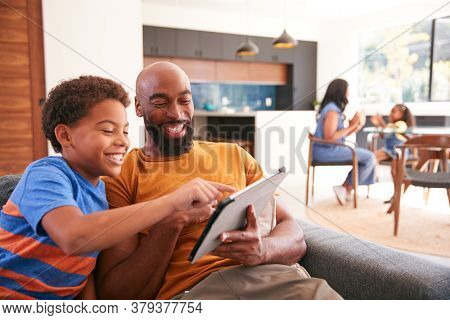 African American Family At Home With Father And Son Sitting On Sofa At Home Using Digital Tablet