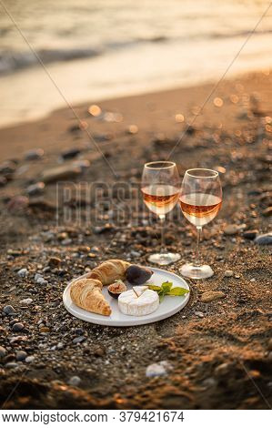 Vertical Image Of The Romantic Beach Picnic For Two At Sunset With Two Glasses Of Rose Wine, Croissa