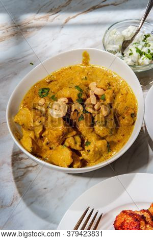 Indian Korma Curry Dinner With Raita On Marble Kitchen Table