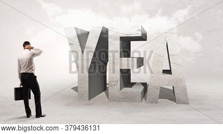 Rear view of a businessman standing in front of YEA abbreviation, attention making concept