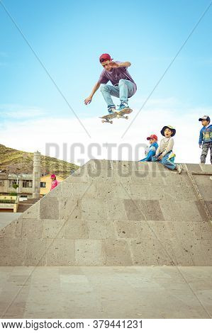 Desaguadero, Puno / Peru - April 4 2016: Young White Man Jumps Monument Gap On His Skateboard In Hug