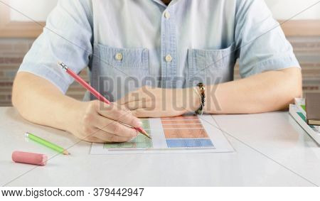 Hand Holding Pencil Over Blurred English Sheet On Desk In Classroom