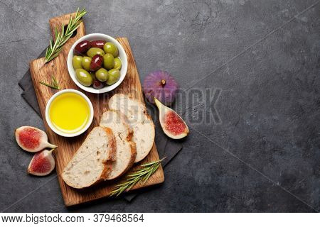 Ripe olives, olive oil, figs and ciabatta bread. Top view flat lay with copy space