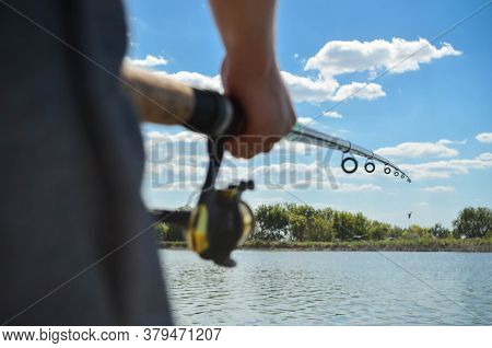 Young Man Throws A Fishing Rod With A Float Into The River For Fishing