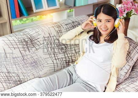 Beautiful Young Pregnant Asian Woman Listening Music With Baby Together By Using Smartphone And Head