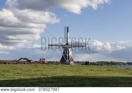 Windmill By The Canal At Glimmen In Holland. Around The Mills Are Excavators And The Background Is A