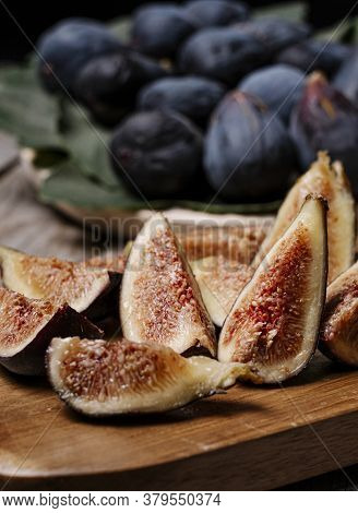 Pieces Of Figs On A Wooden Board, At The Bottom Figs On A Tray With The Leaf Of The Fig Tree
