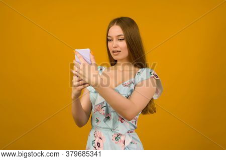 Young Woman Wears In Sunner Dress With Flowers Surprised By The News On A Smartphone - Image
