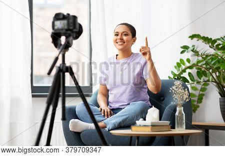 blogging, videoblog and people concept - happy smiling african american female video blogger with camera videoblogging at home
