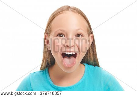 Emotional eight year old girl is teasing someone with his tongue out. Studio portrait on a white background. Copy space