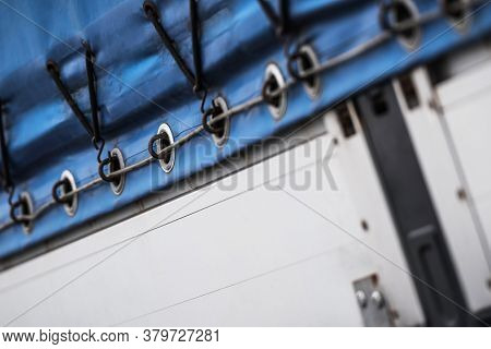 Detailed Close Up Of Blue Tarp Tight With Ropes To Top Of Semi Trailer.