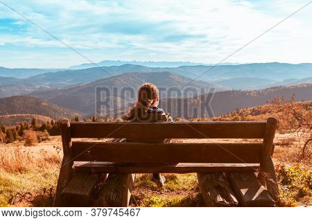 A Lonely Girl Sits On A Bench And Enjoys The Stunning View Of The Autumn Mountains