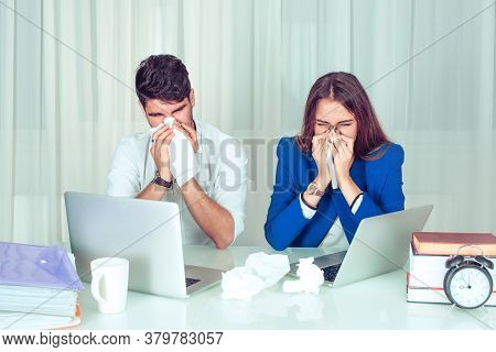 Young Man And Woman Couple Colleagues Blowing Nose With Tissues While Working Sitting Together At Ta
