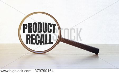Magnifying Glass With Text Product Recall On Wooden Table.