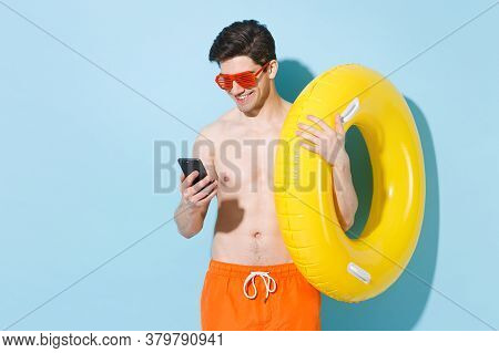 Smiling Young Man Guy In Eyeglasses Hold Inflatable Ring Isolated On Blue Background Studio. People 