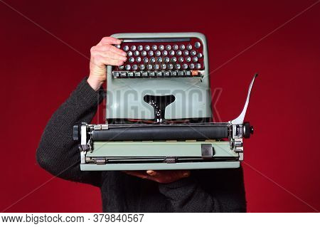 Man Holding A Typewriter On Red Background