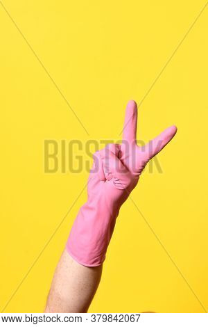 Hand With Glove And V Sign On Yellow Background