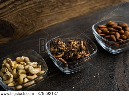 Almond, Cachew And Walnut In A Small Plates Which Standing On A Black Table. Nuts Is A Healthy Veget